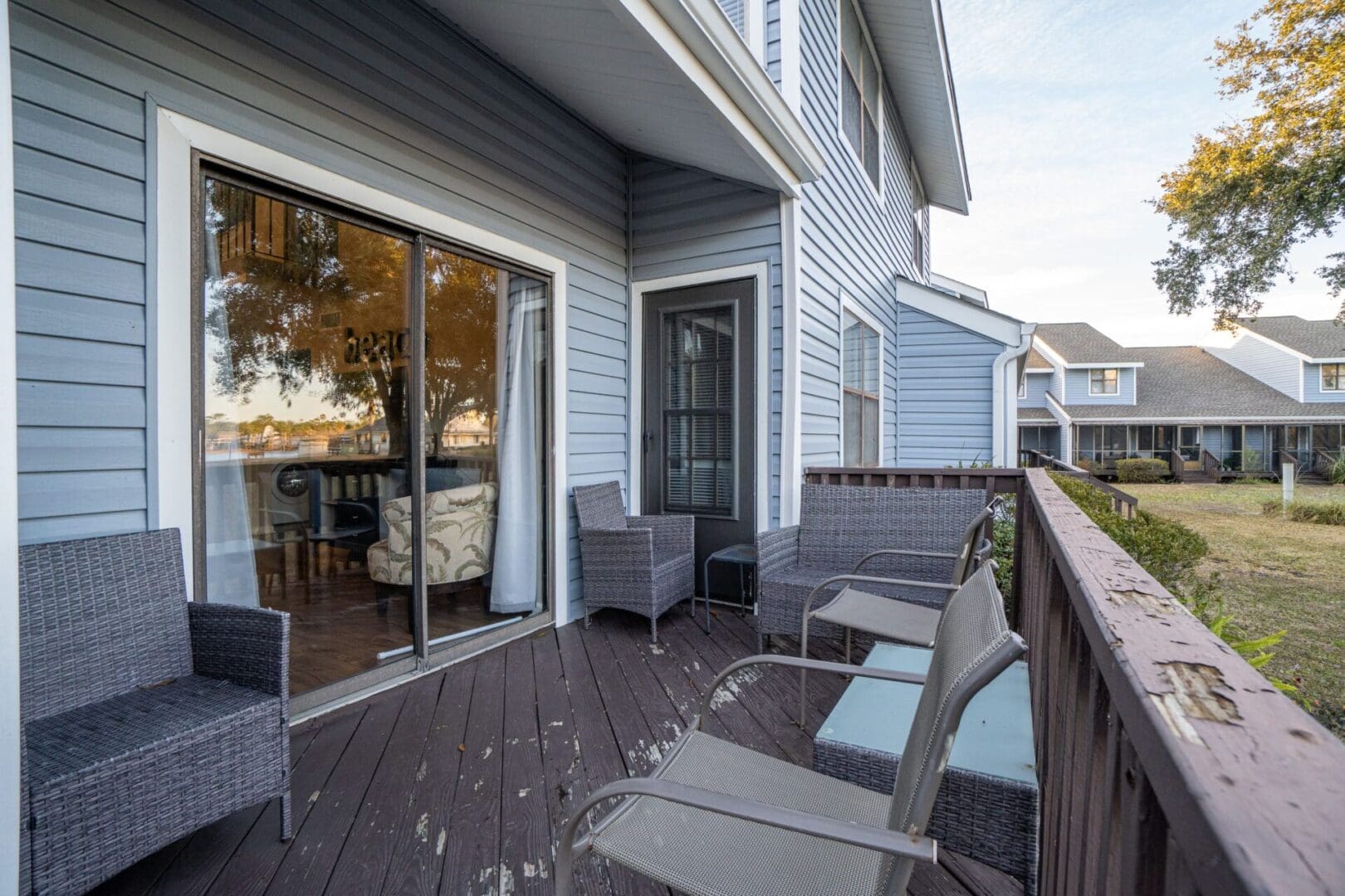 A deck with chairs and tables outside of the house.