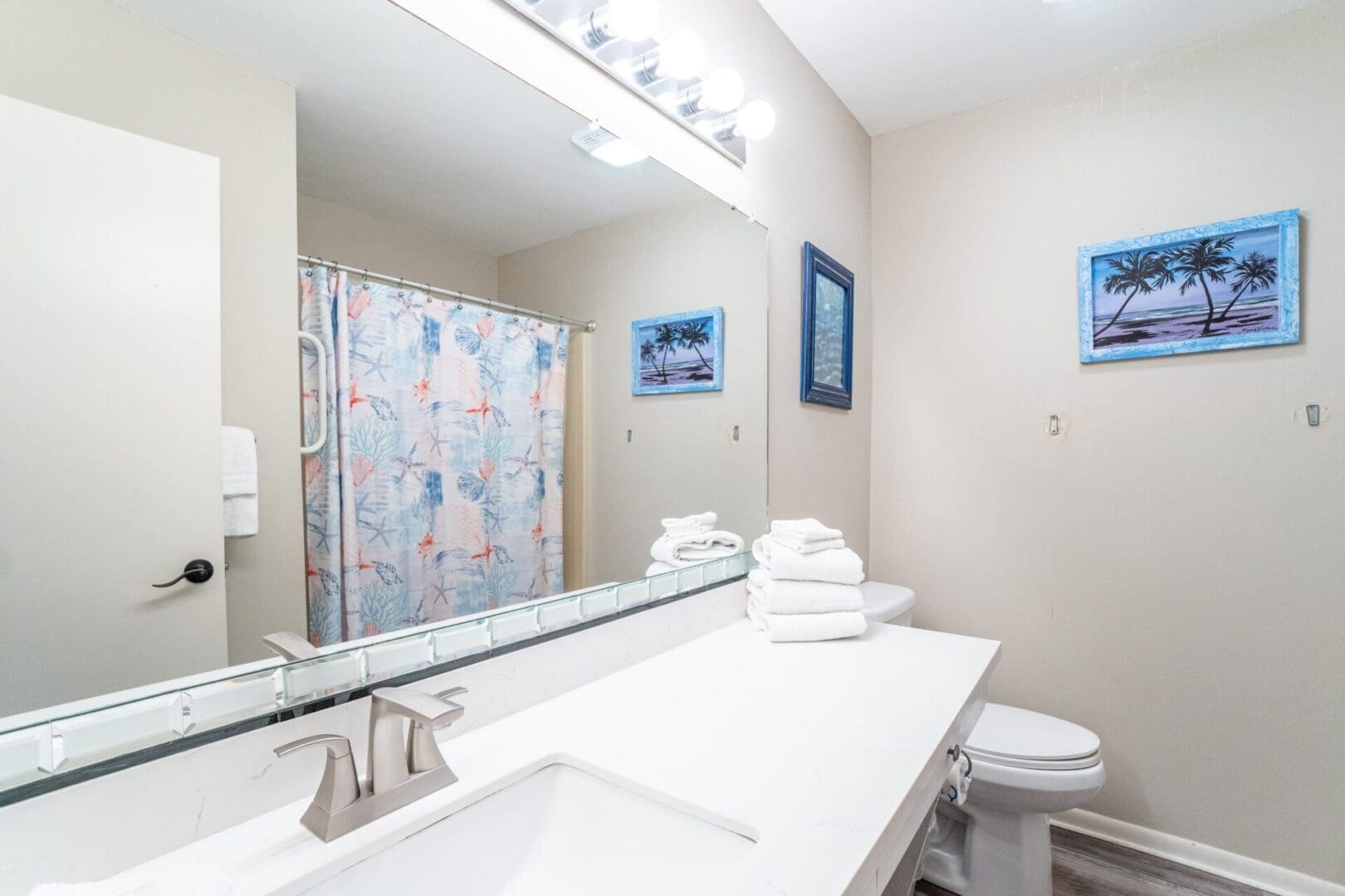 A bathroom with a sink, toilet and mirror.