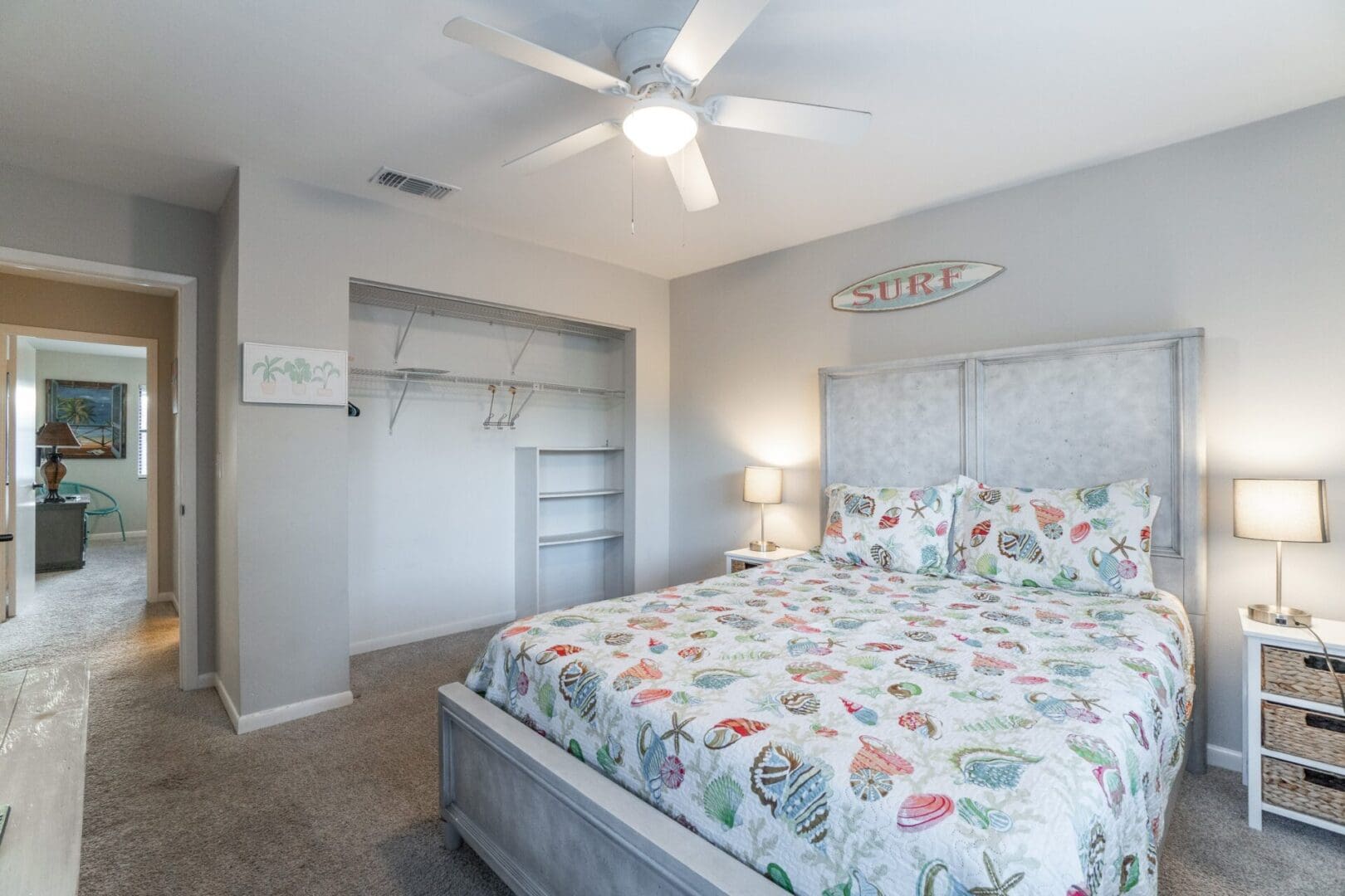 A bedroom with a bed, dresser and ceiling fan.