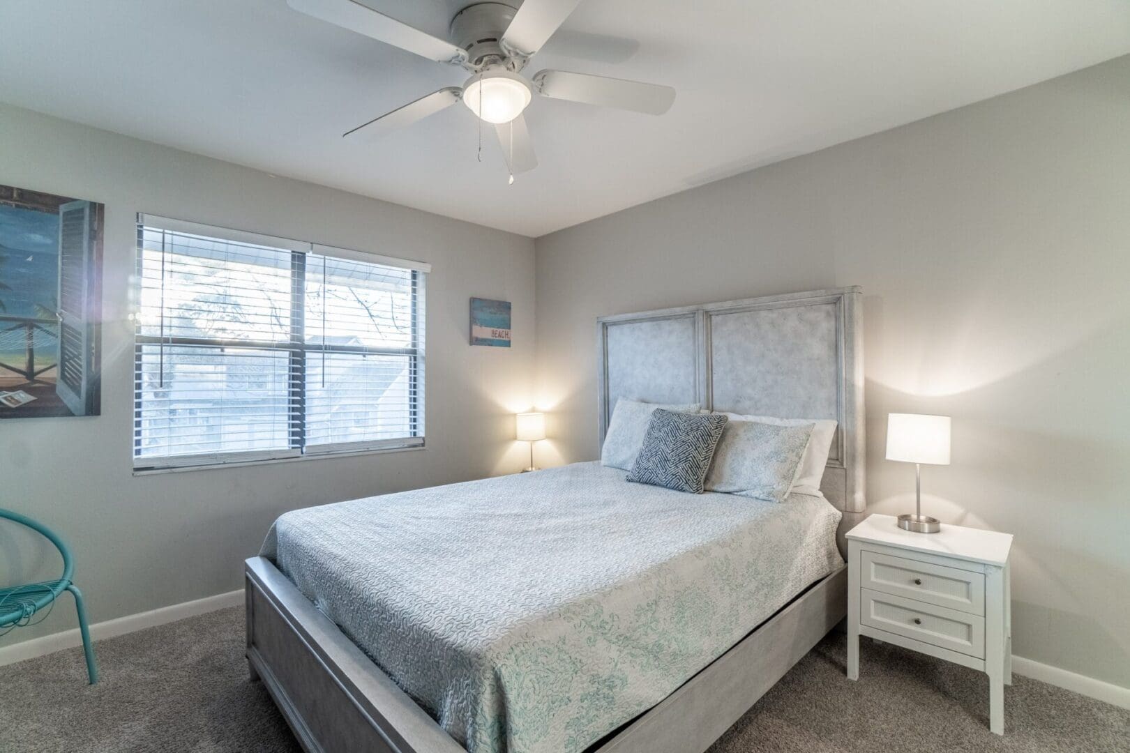 A bedroom with a bed, nightstand and ceiling fan.