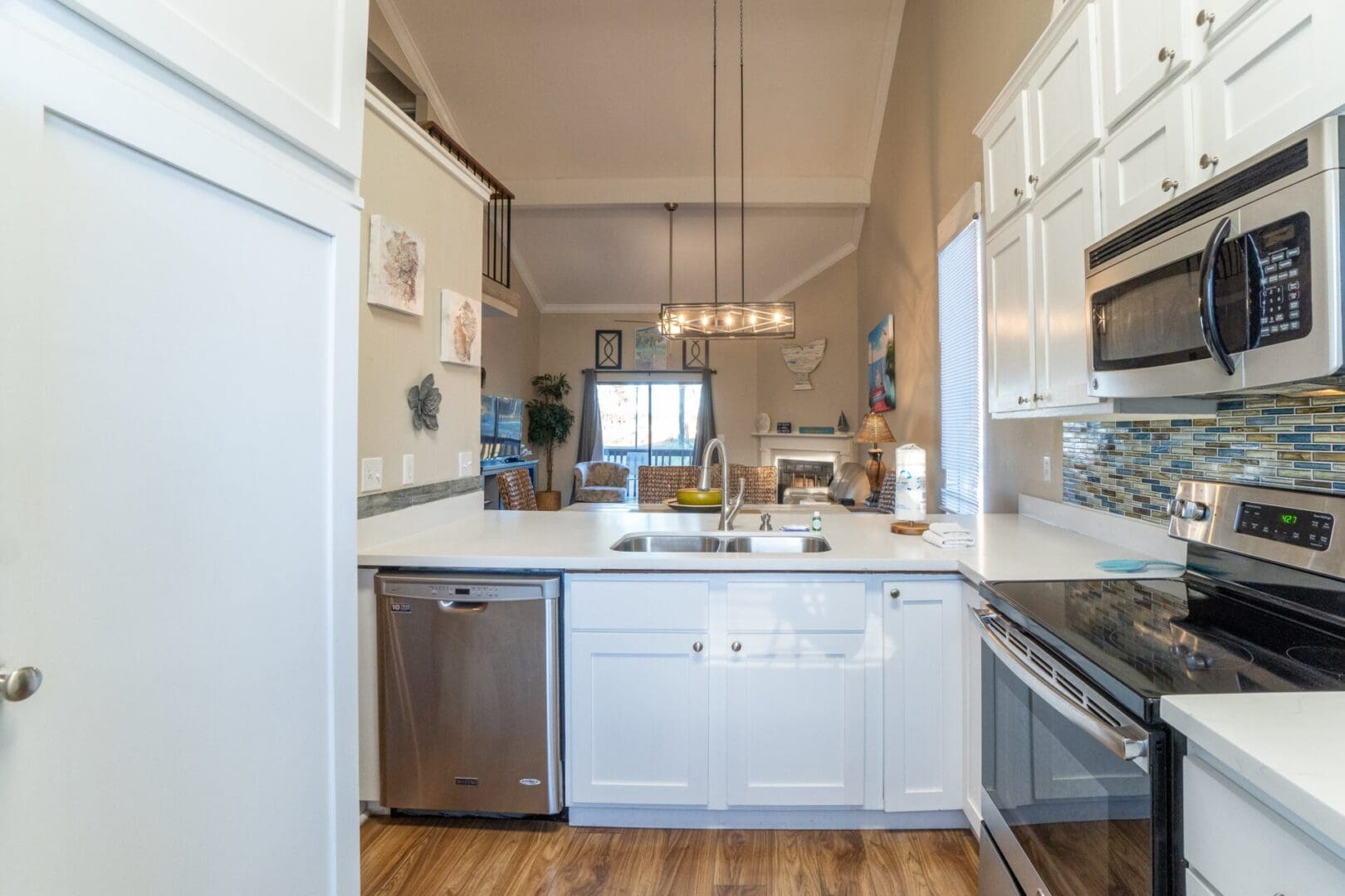 A kitchen with white cabinets and wooden floors.