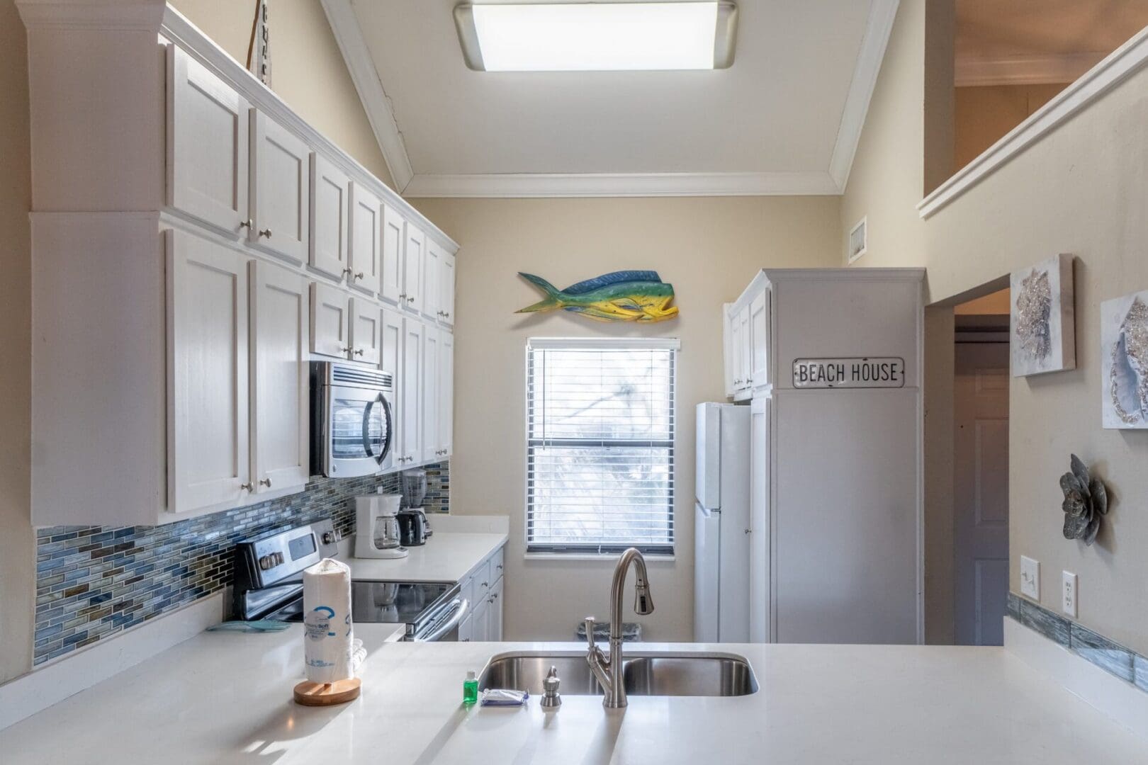 A kitchen with white cabinets and a fish picture on the wall.