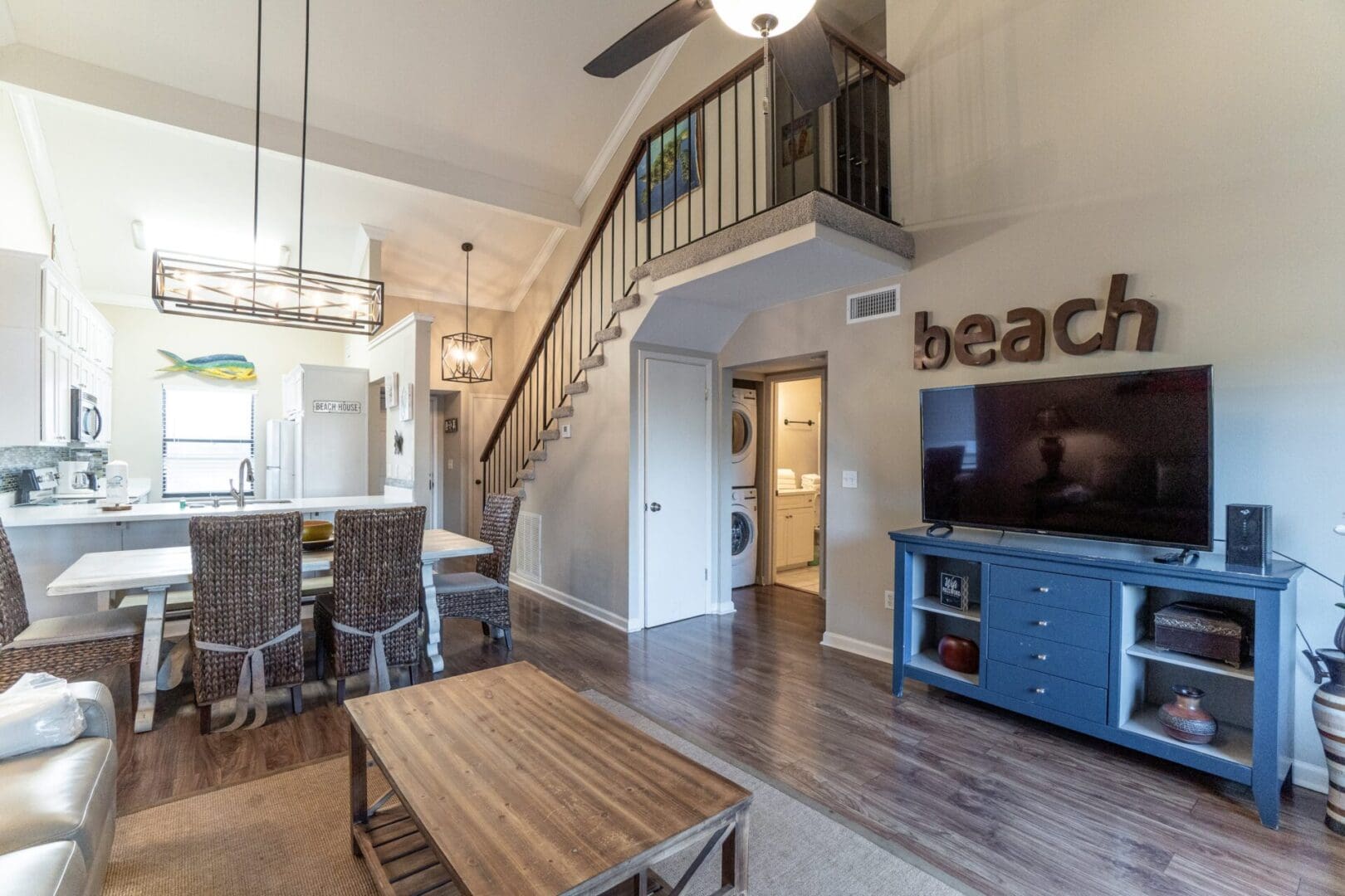 A living room with a table and chairs, tv on the wall.