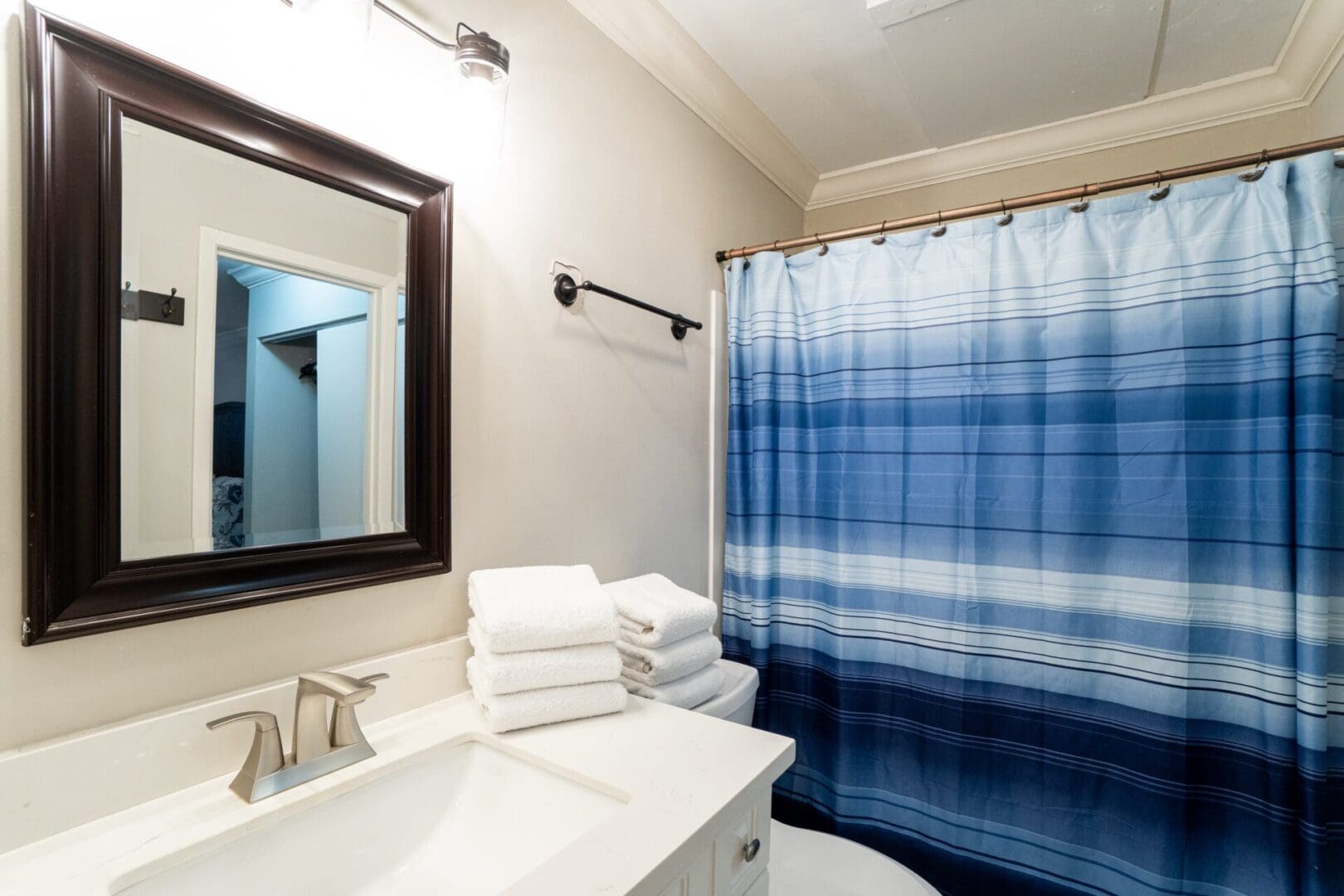 A bathroom with a sink, mirror and shower curtain.