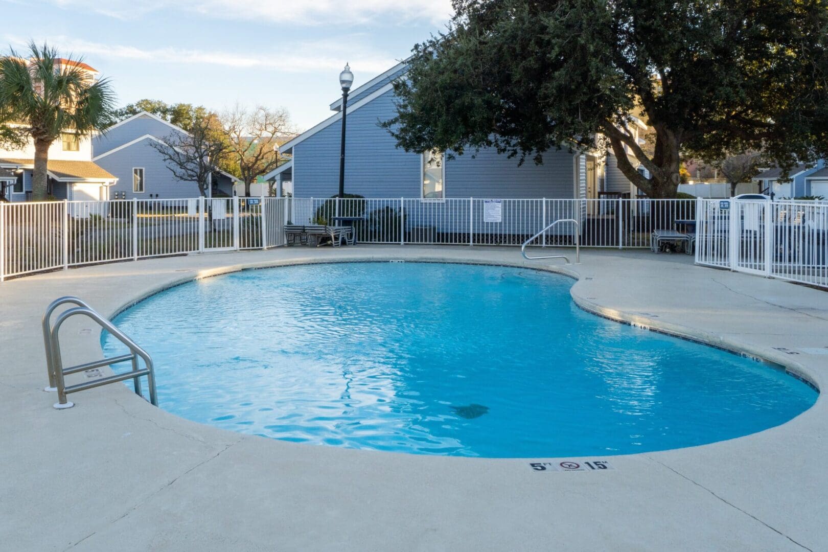 A pool with a fence around it and trees in the background.