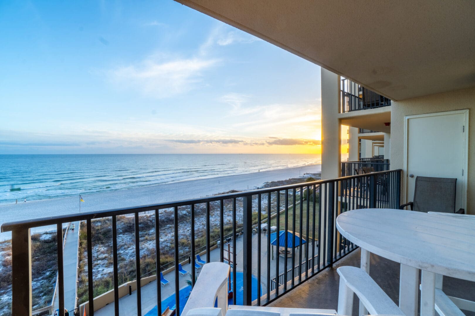 A balcony with chairs and tables overlooking the ocean.