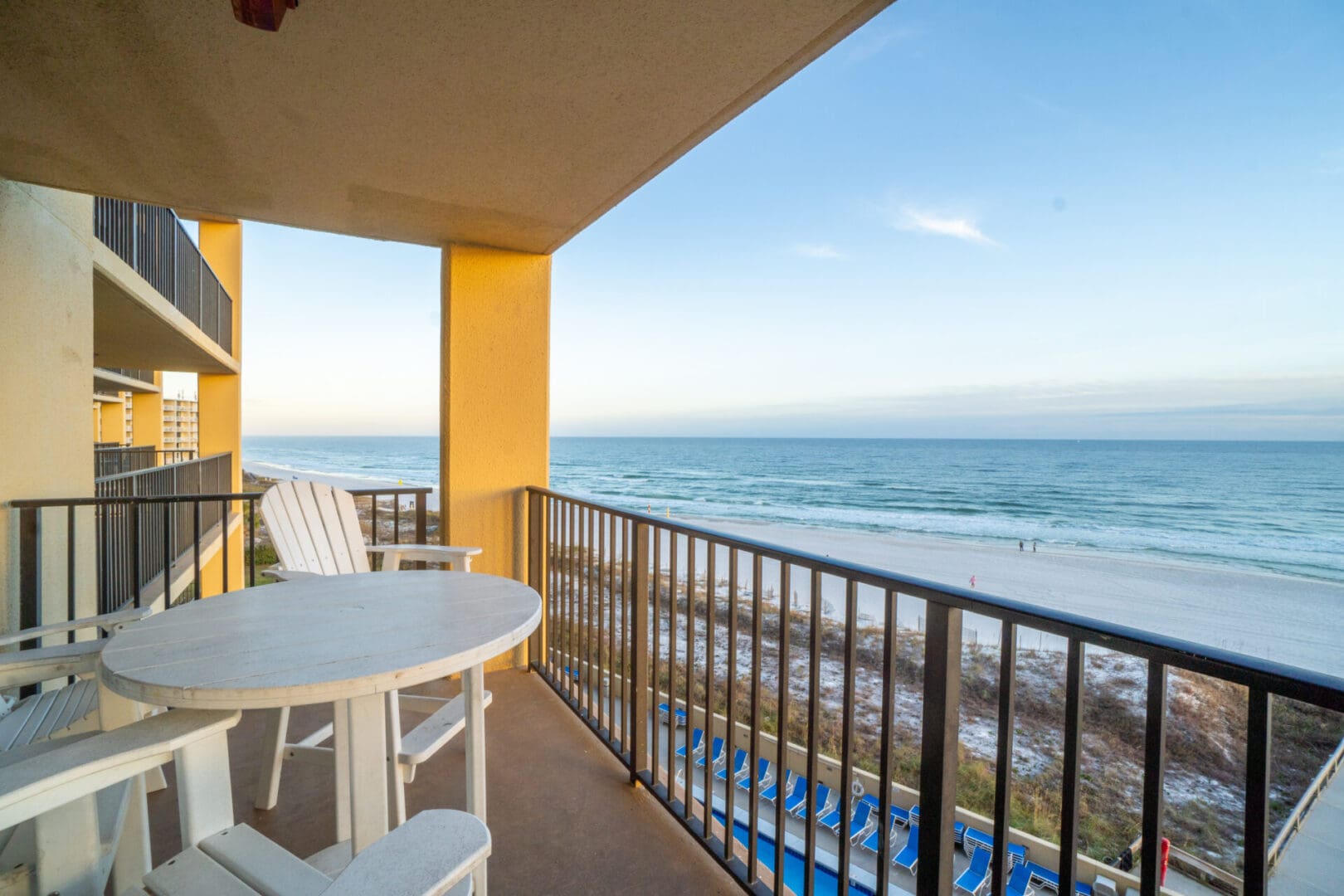 A balcony with chairs and tables overlooking the ocean.