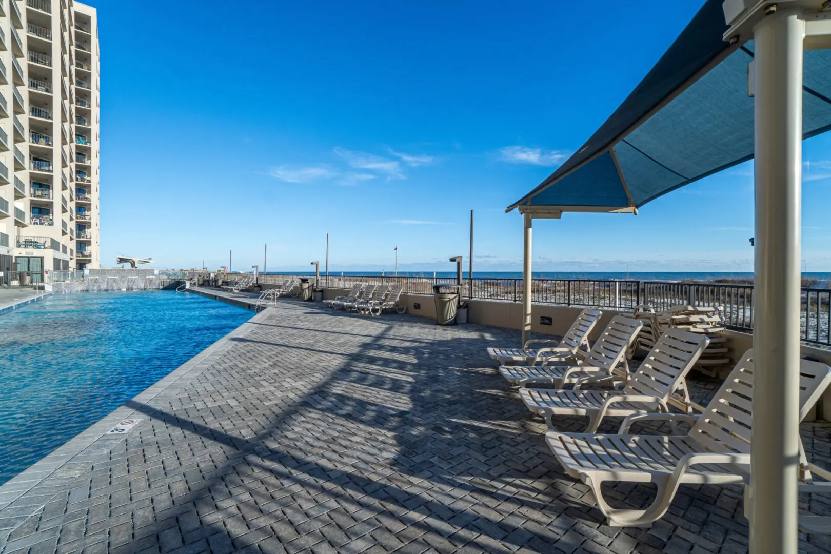 A beach with chairs and umbrellas next to the pool.