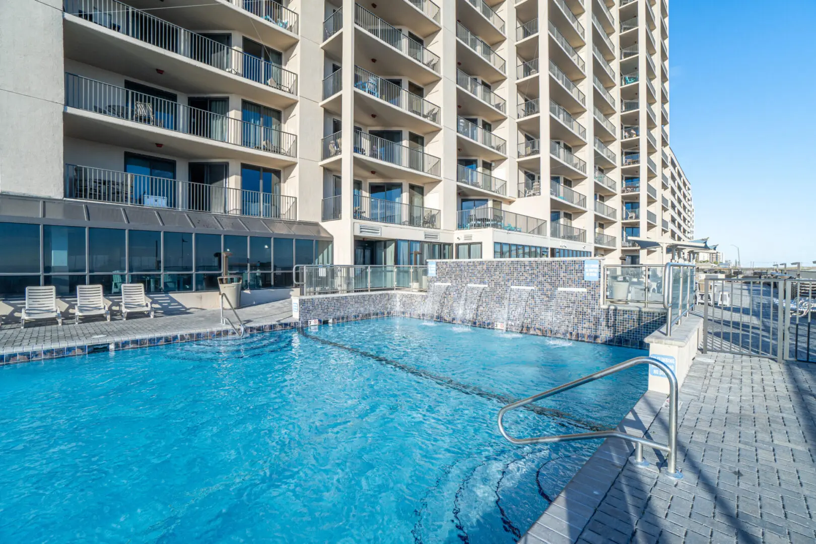 A pool with chairs and a building in the background