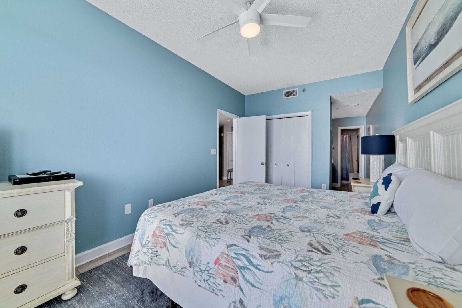 A bedroom with blue walls and white bedding.