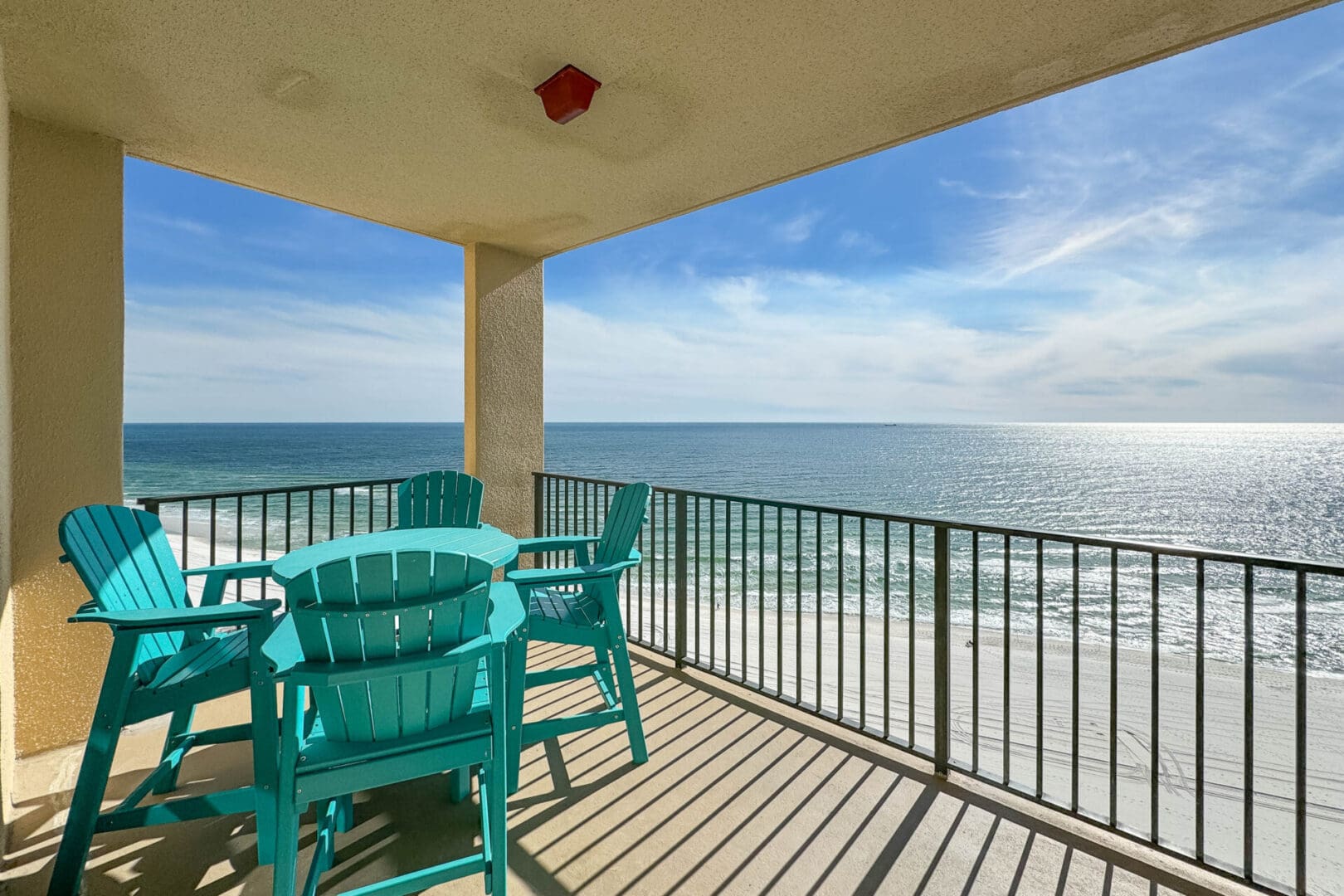 A balcony with chairs and tables overlooking the ocean.