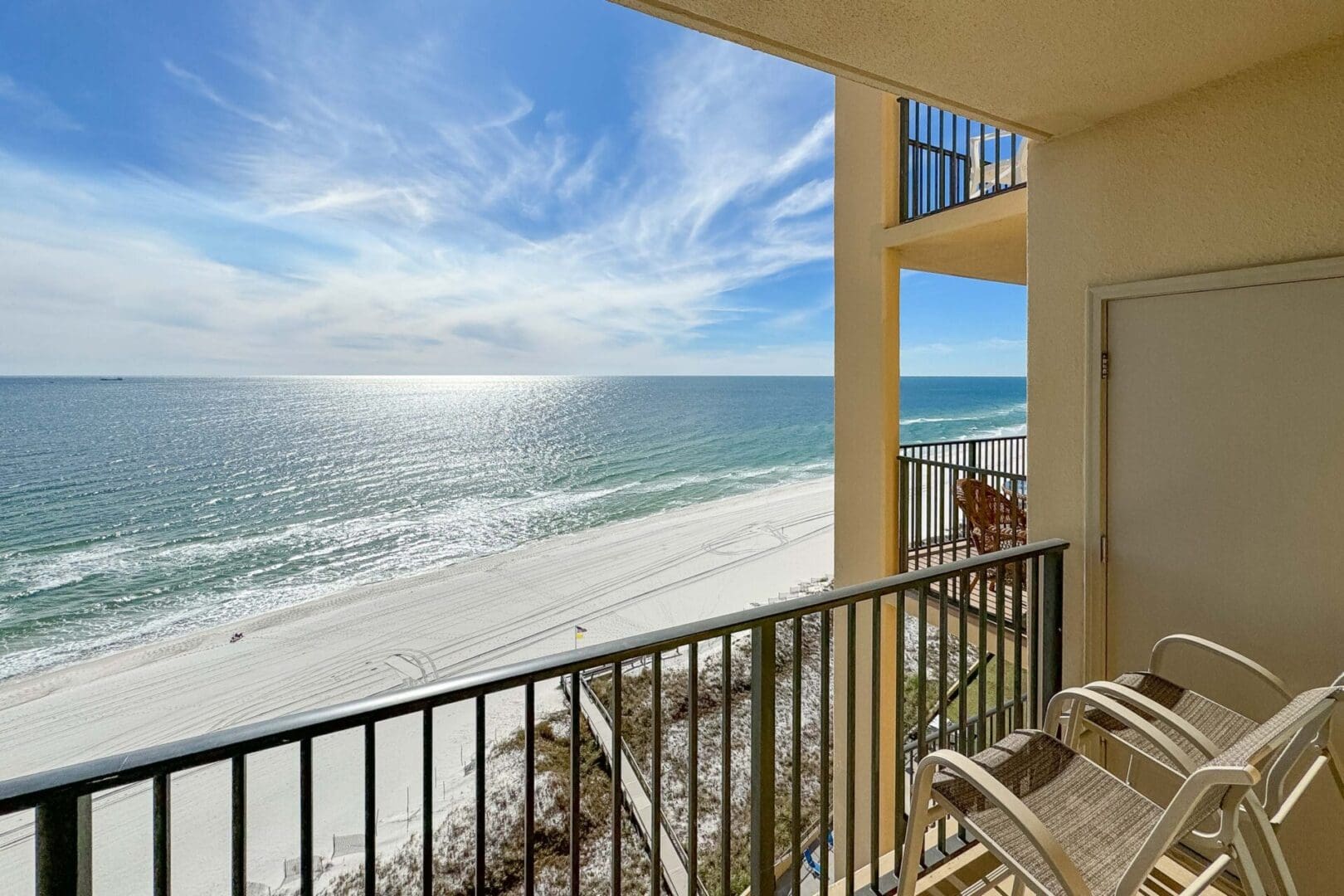 A balcony with chairs and tables overlooking the ocean.