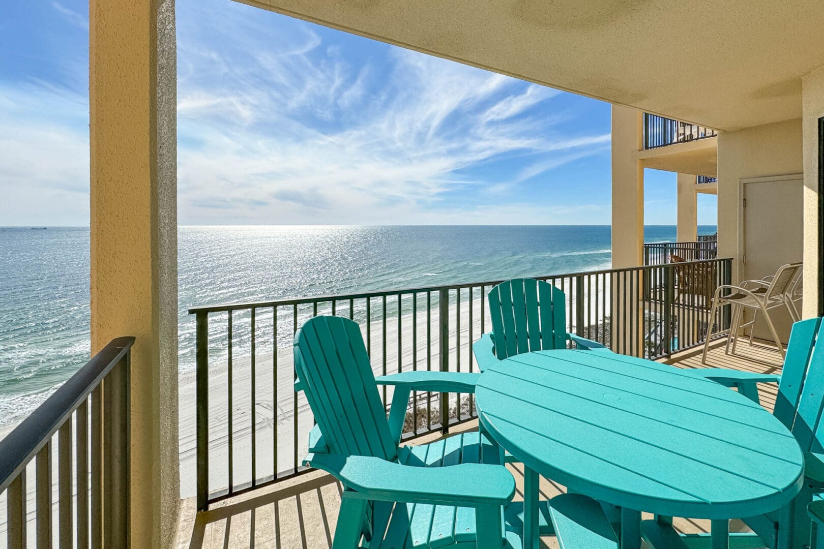 A balcony with chairs and table overlooking the ocean.