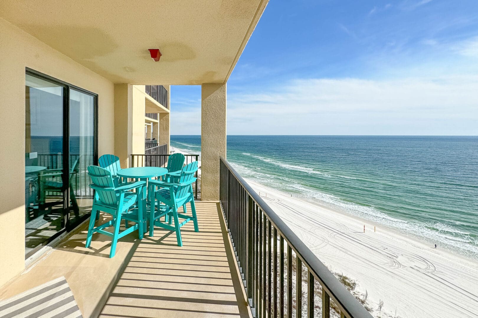 A balcony with chairs and tables overlooking the ocean.