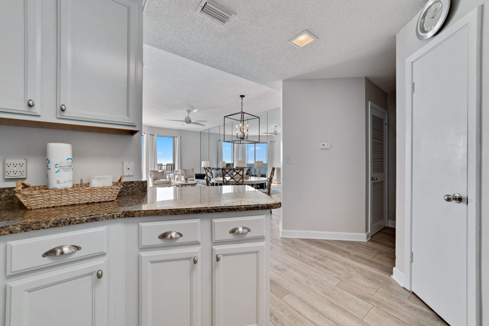 A kitchen with white cabinets and wood floors.