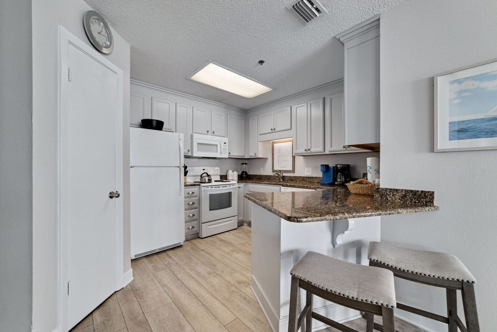 A kitchen with white cabinets and wooden floors.