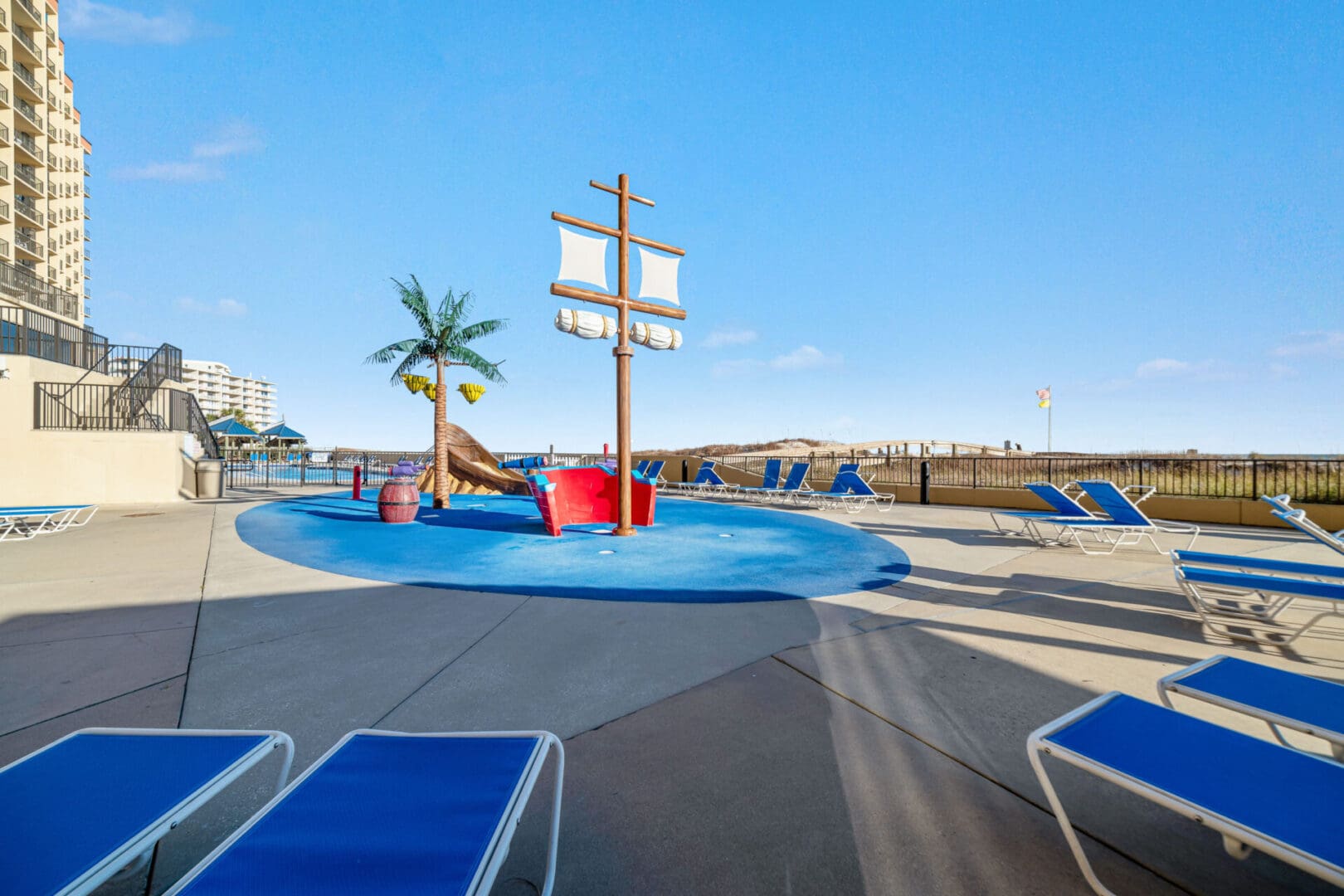 A pool with blue chairs and a slide.