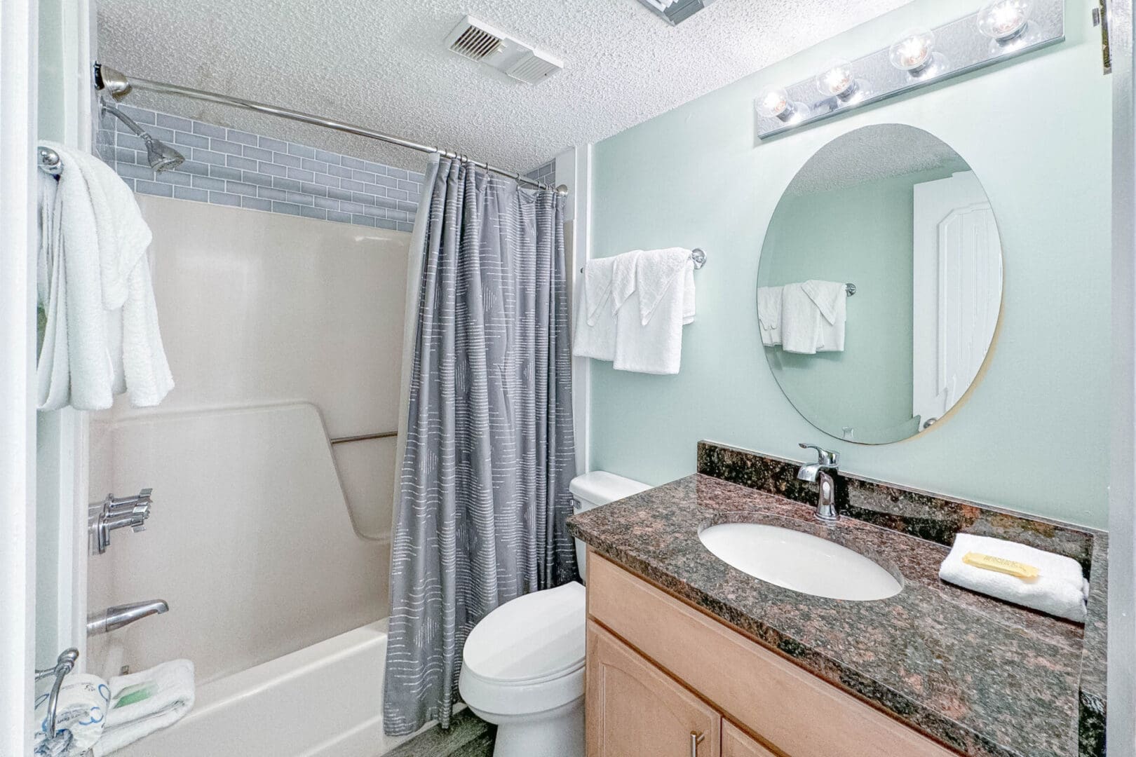 A bathroom with a toilet, sink and mirror.