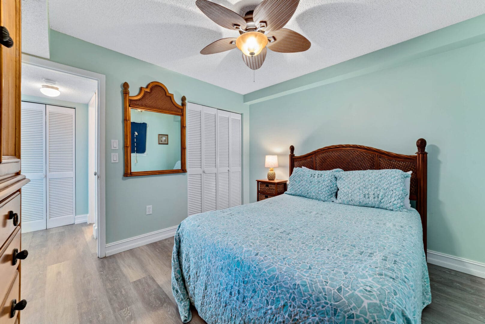 A bedroom with a bed, dresser and mirror.