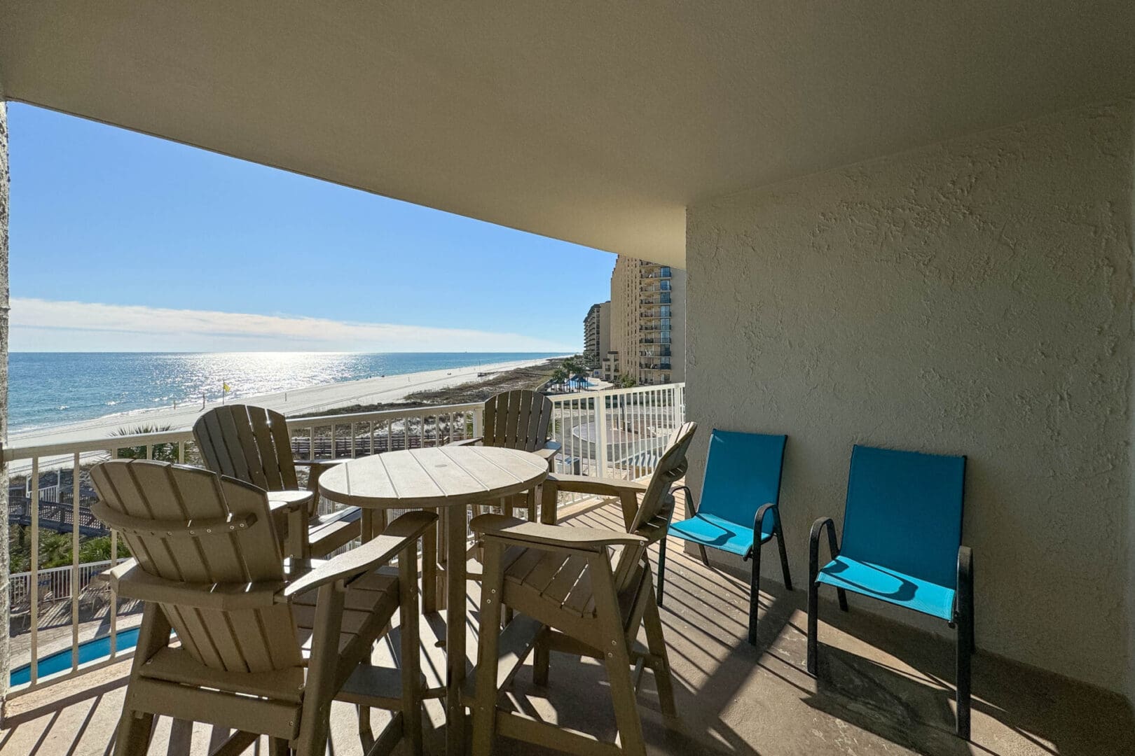 A balcony with chairs and tables overlooking the ocean.