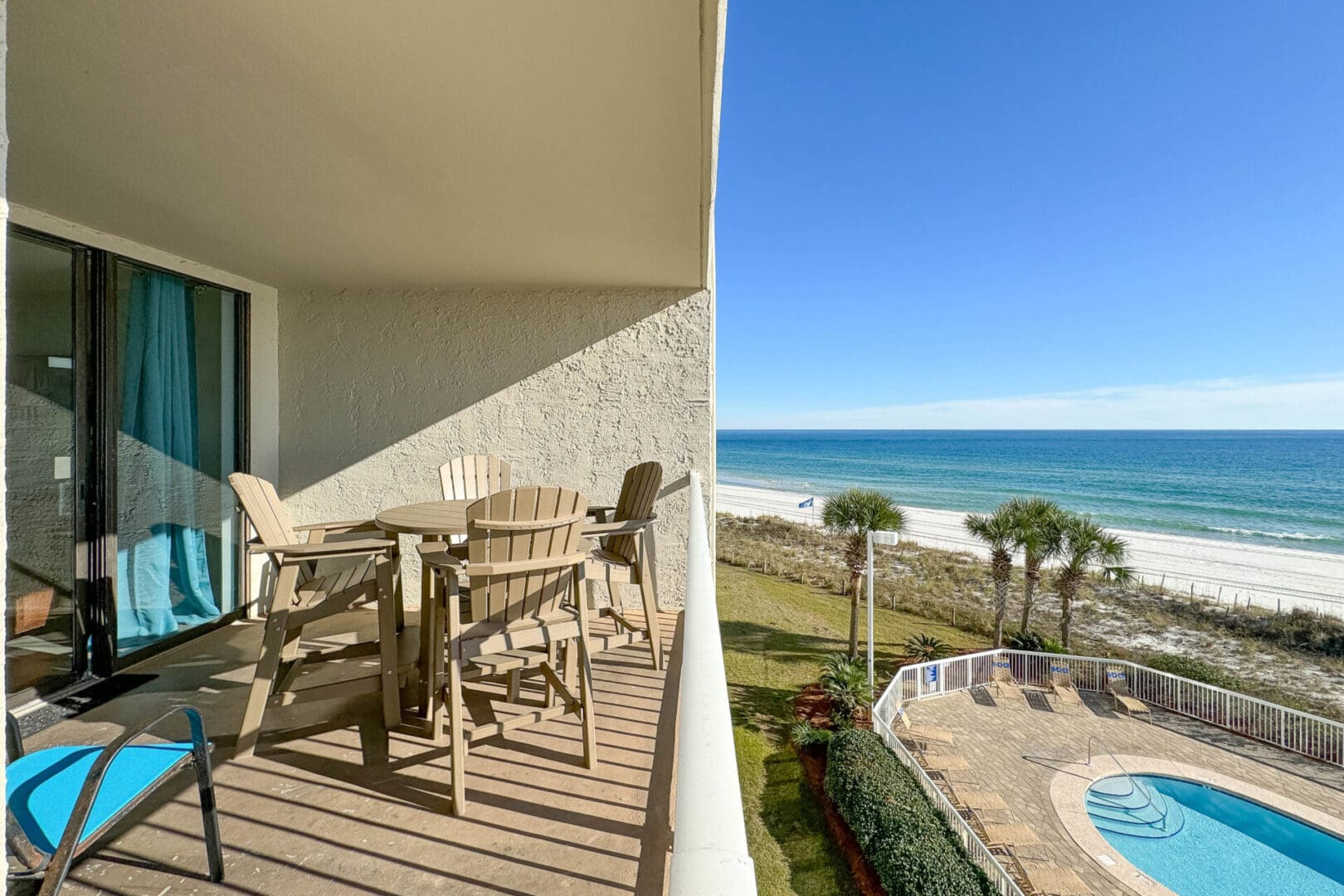 A balcony with chairs and tables overlooking the ocean.