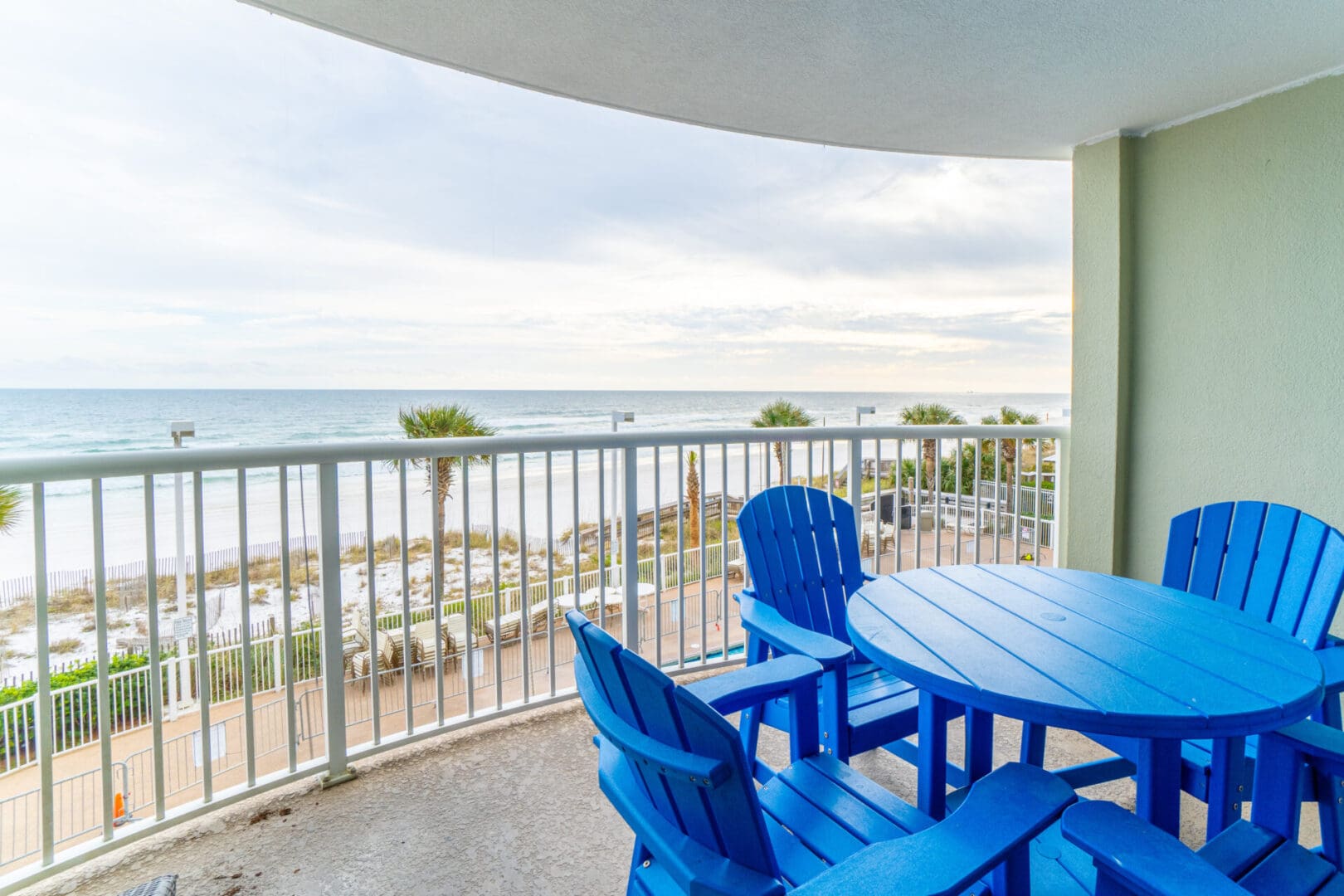 A balcony with chairs and table overlooking the ocean.