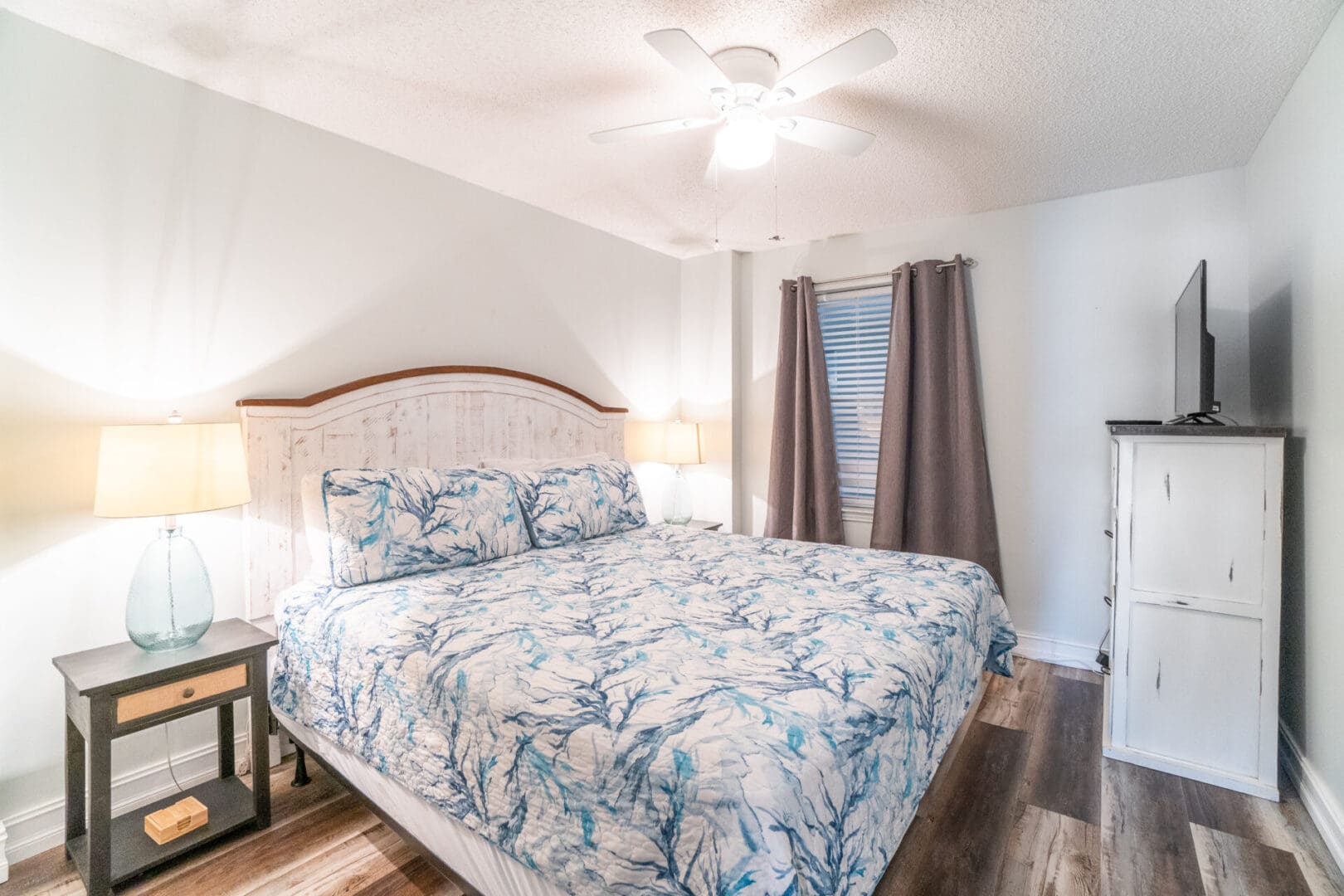 A bedroom with a bed, nightstand and window.