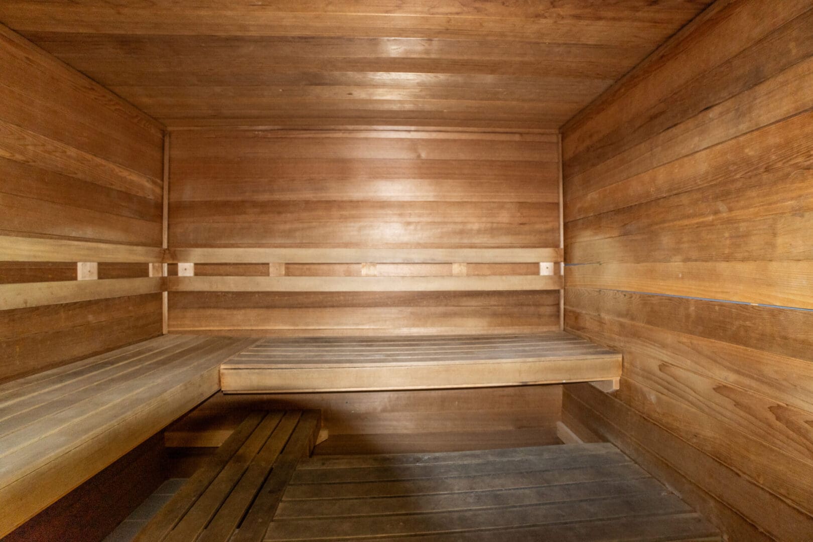 A wooden room with two beds and benches.