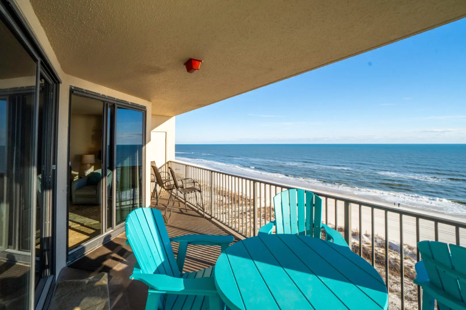 A balcony with chairs and table overlooking the ocean.