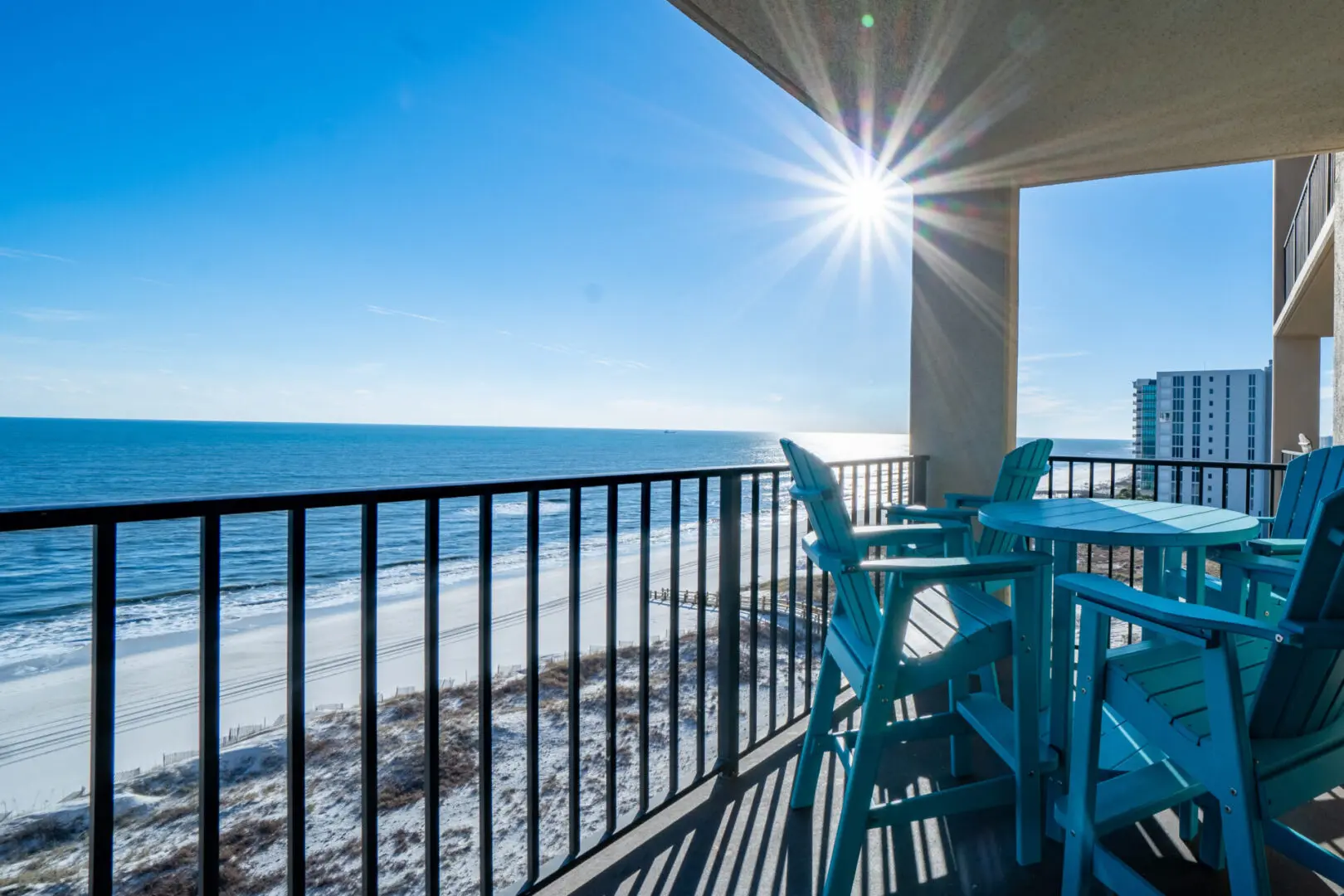 A balcony with chairs and tables overlooking the ocean.