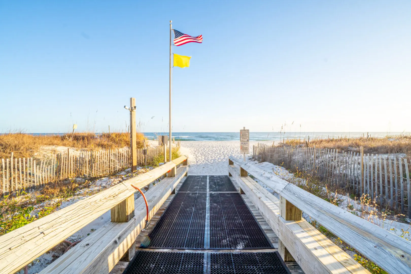 A boardwalk with an empty walkway and the beach in the background.