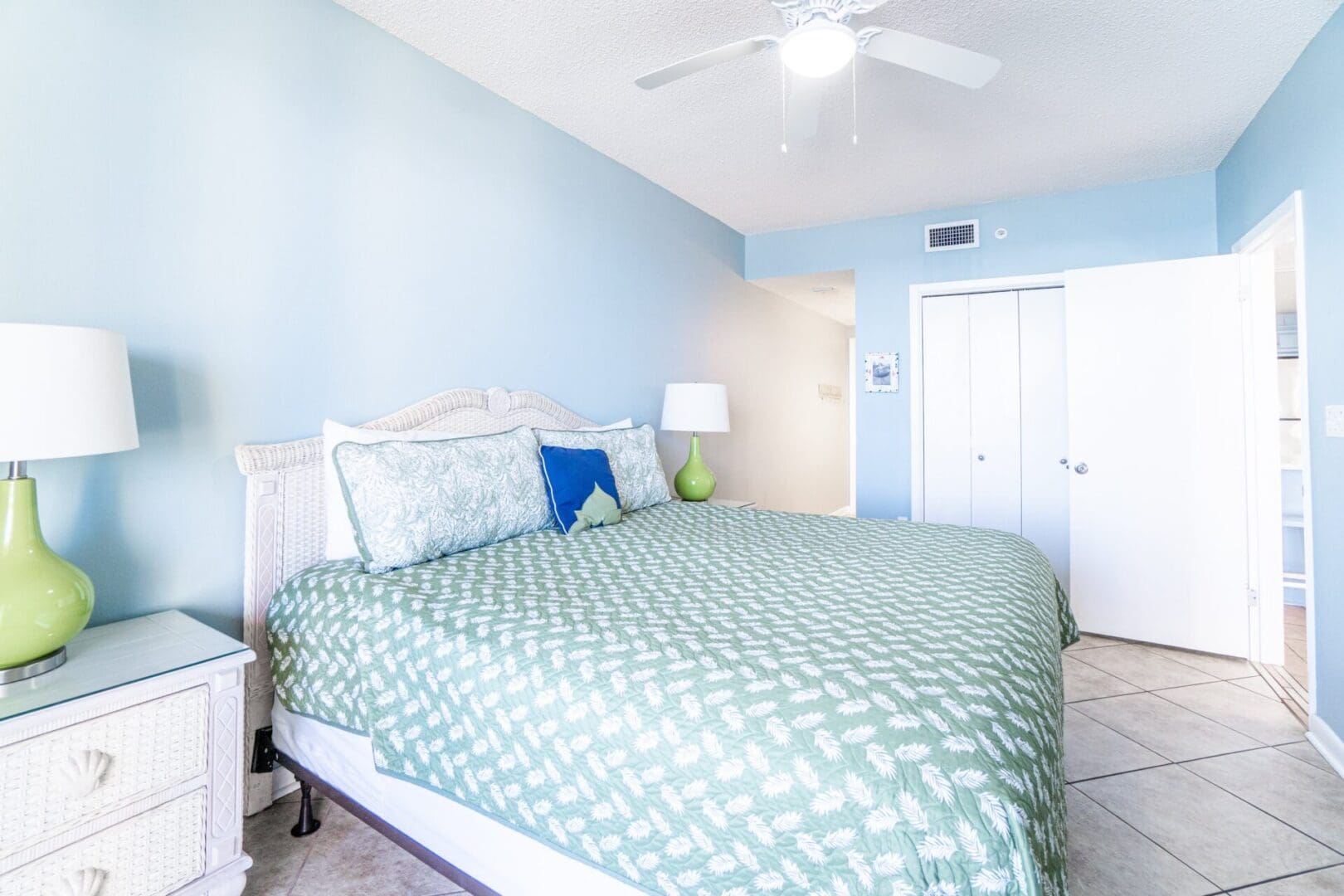 A bedroom with a bed, ceiling fan and door.