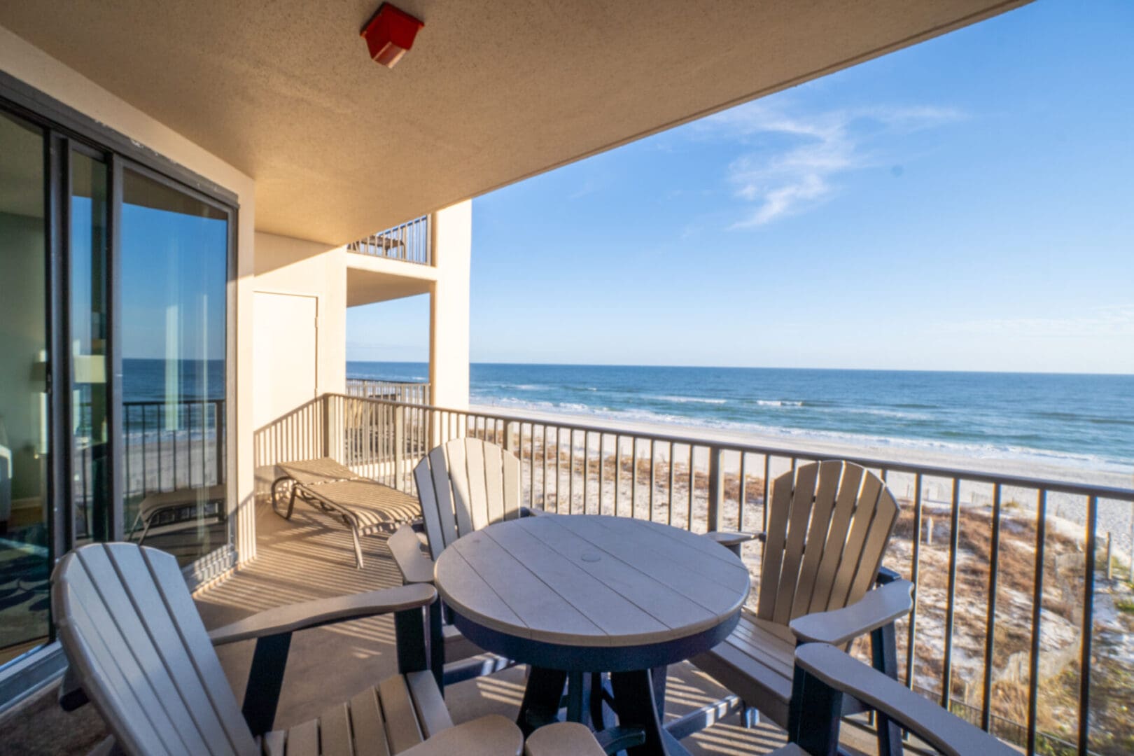 A balcony with chairs and tables overlooking the ocean.