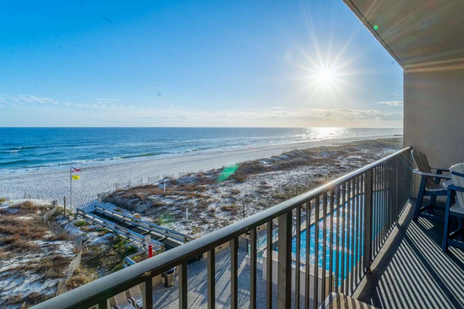 A balcony with a view of the beach and ocean.