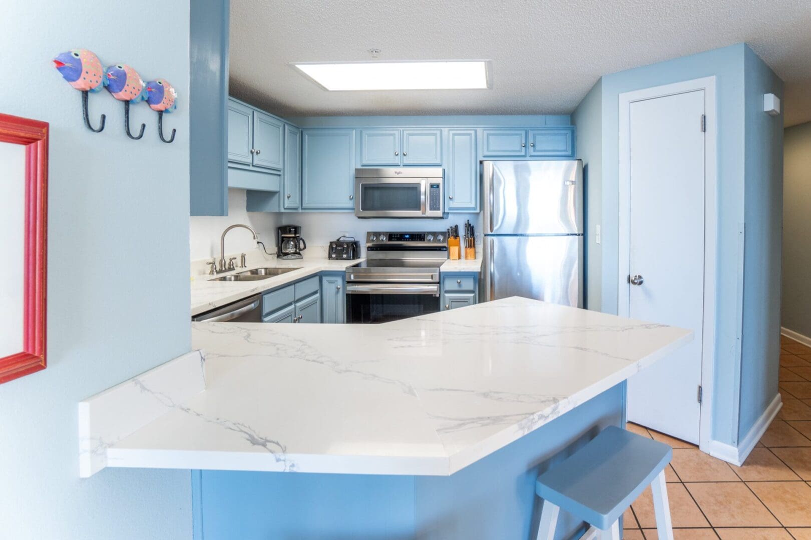 A kitchen with blue cabinets and white counter tops.