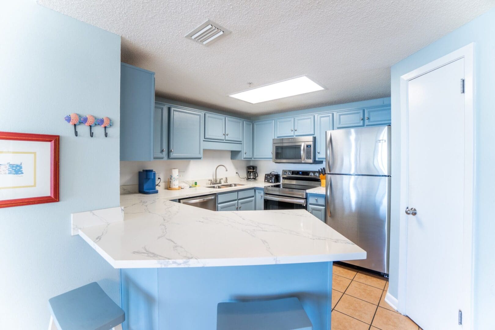 A kitchen with blue cabinets and white counter tops.