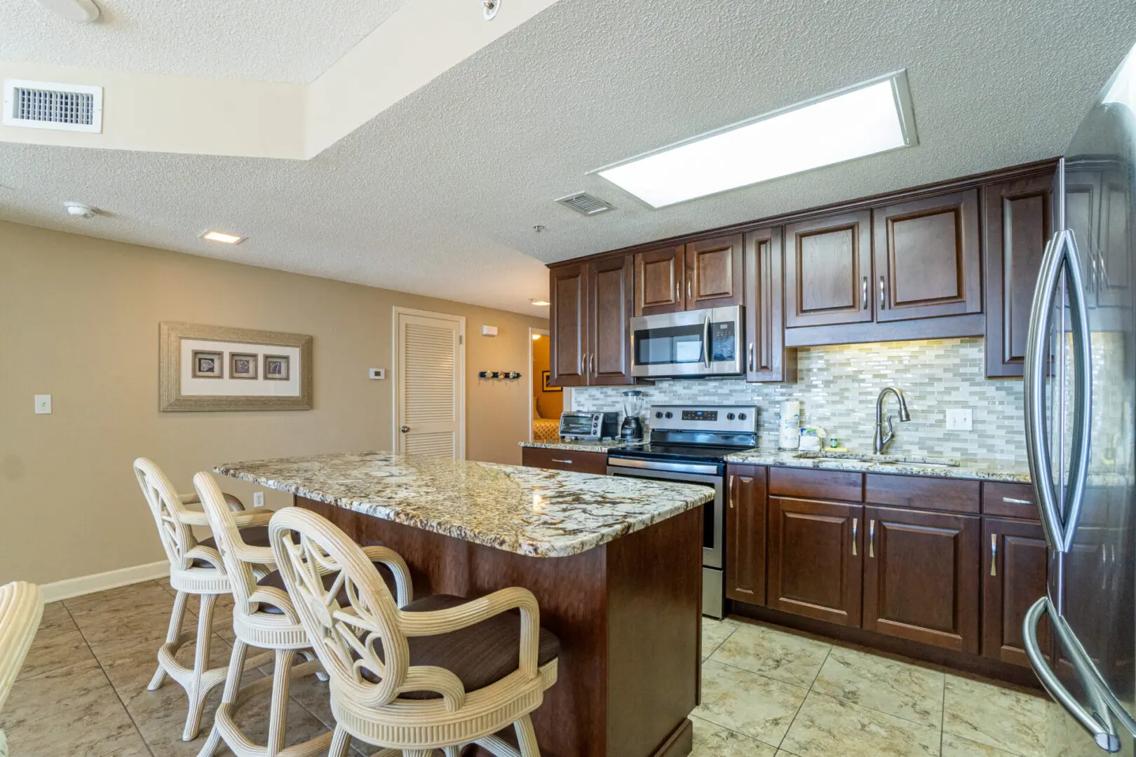 A kitchen with a large island and chairs.