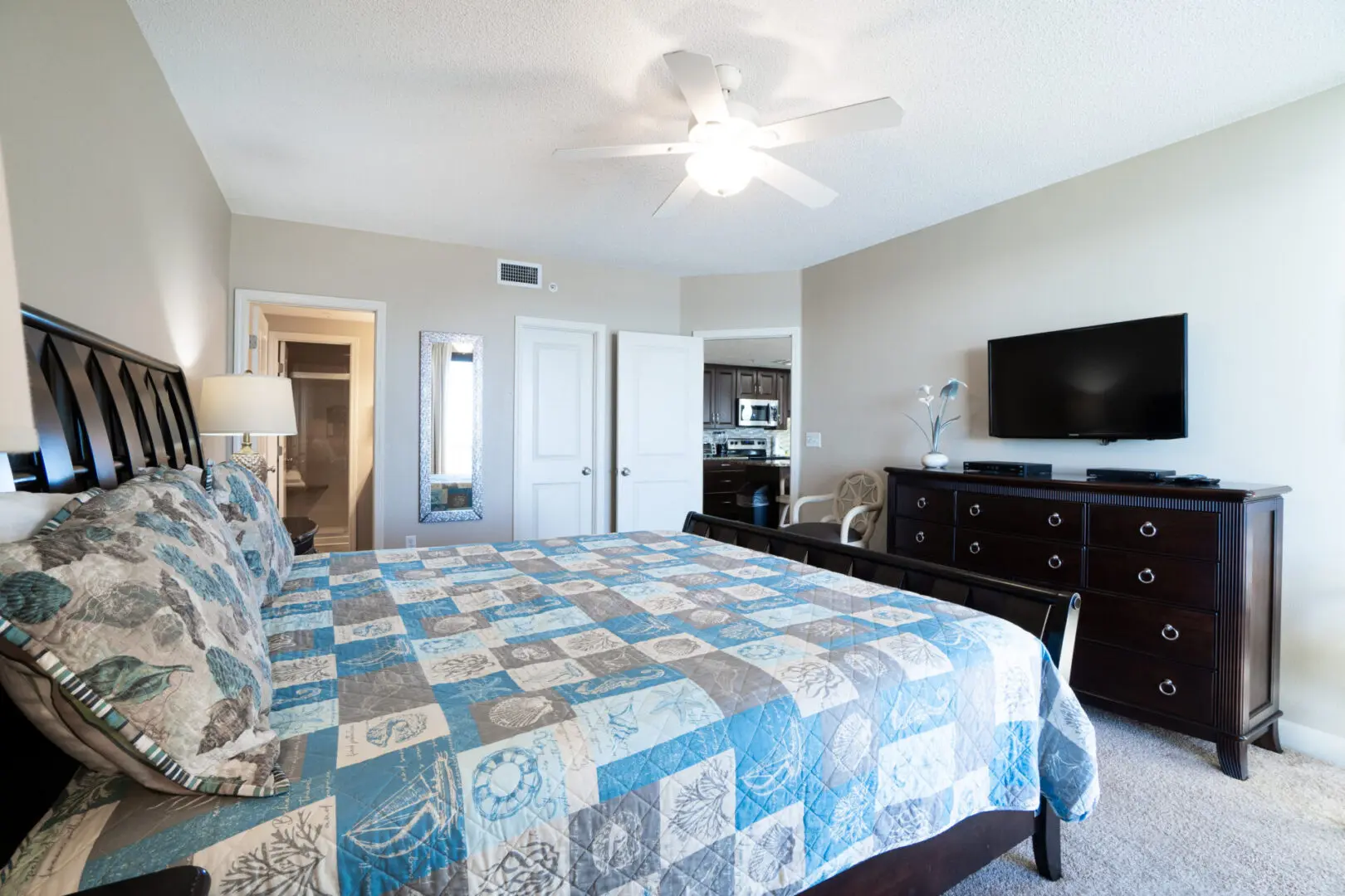 A bedroom with a bed, dresser and tv.