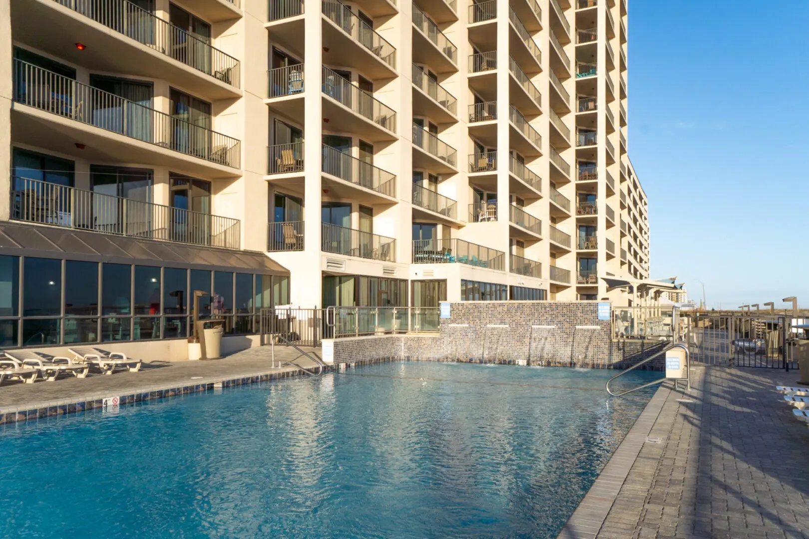 A pool in front of a building with balconies.